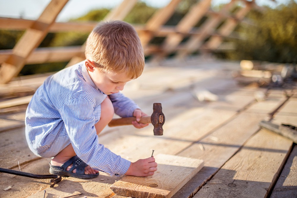 Jongetje slaat spijker in plank