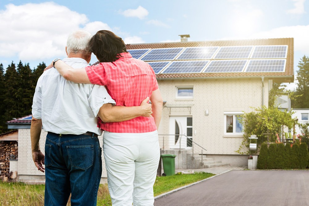 Ouder echtpaar staat voor woning met zonnepanelen 