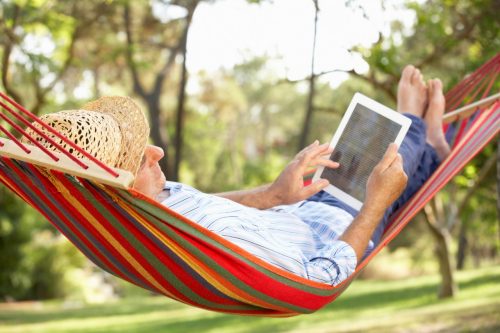 Seniore man ligt in hangmat met tablet