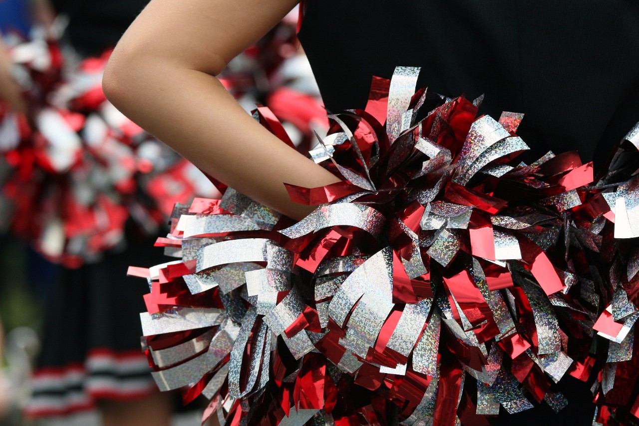 Cheerleader houdt pompoenen achter haar rug