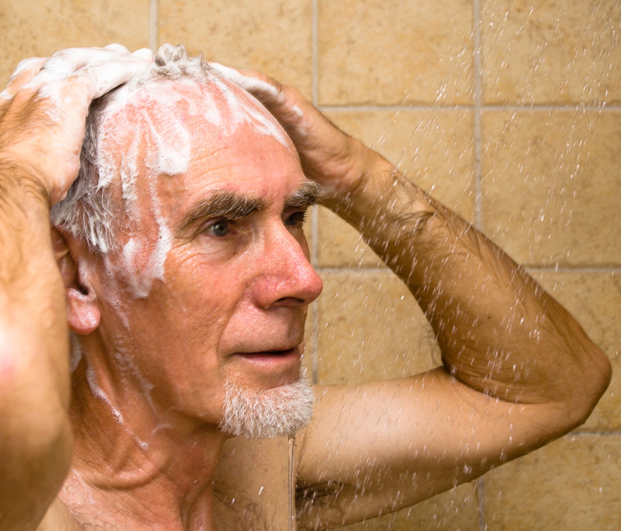 Senior wast zijn haren onder de douche