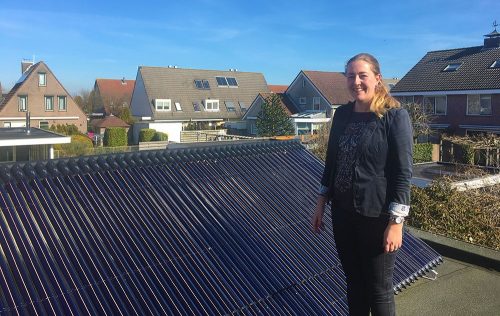 Desiree Kon naast de zonnecollectoren op het dak