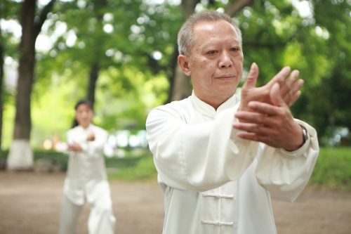 Oudere deelnemer aan Tai Chi in Japan in de buitenlucht