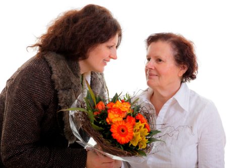 Zittende dame en staande dame met boeket bloemen