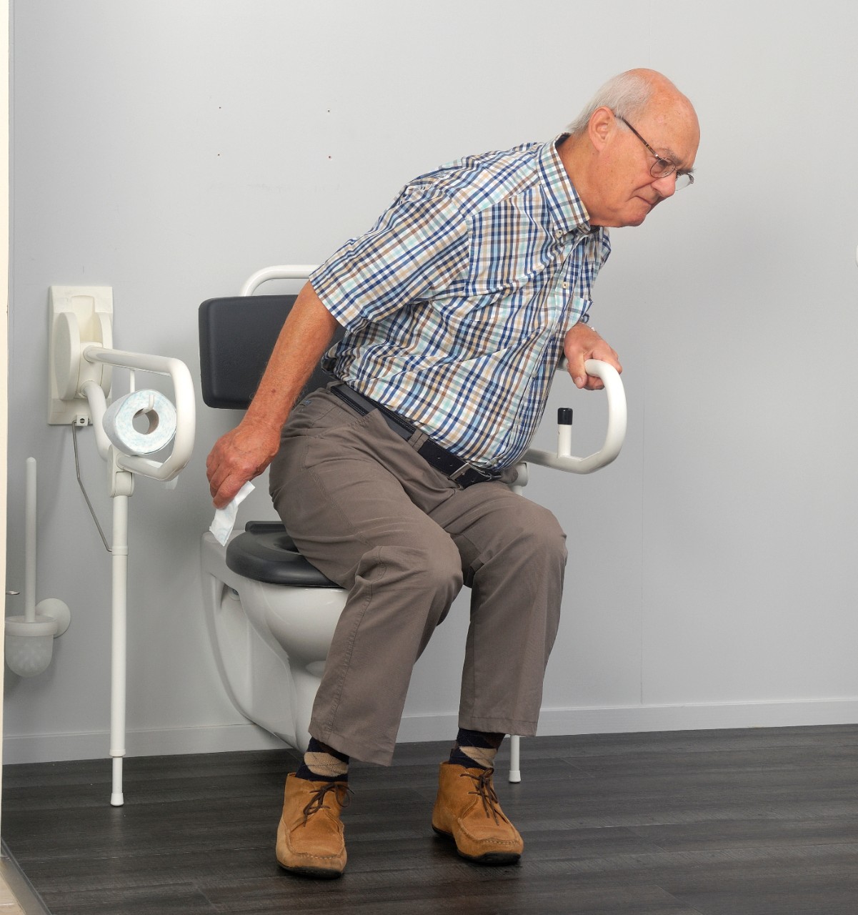 Meneer houdt zich vast aan opklapbare beugels rondom de wc