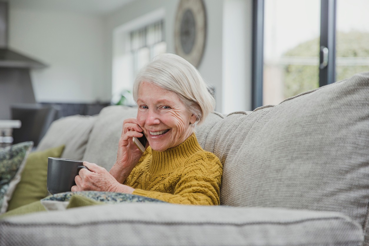 Mevrouw op bank met iPhone en thee