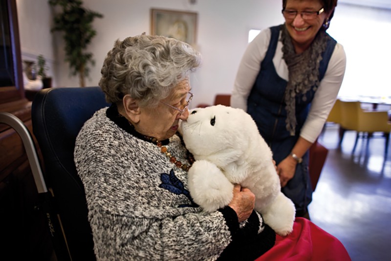 Dementerende vrouw knuffelt Paro, de knuffelrobot