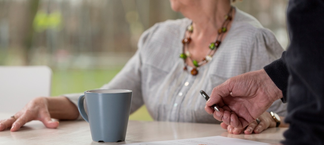 Gesprek over Wmo woningaanpassingen met een oudere mevrouw aan tafel