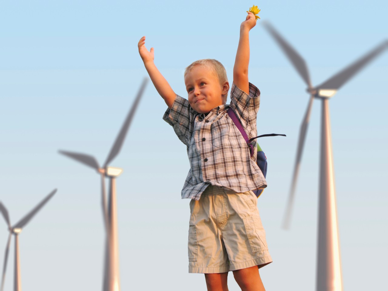 Kind met bloem in de hand en rugzak voor een rij windmolens