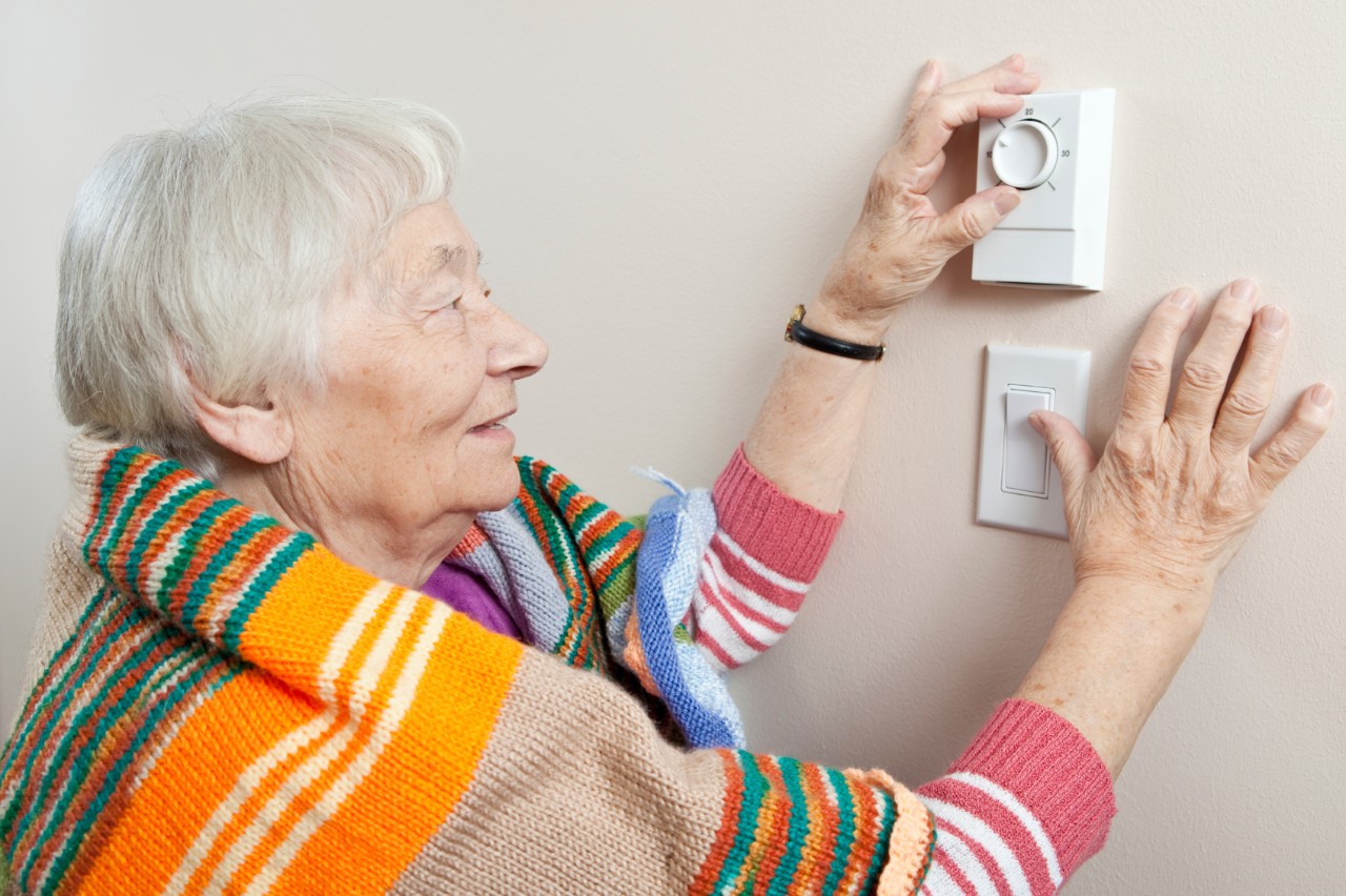 Mevrouw regelt haar thermostaat.