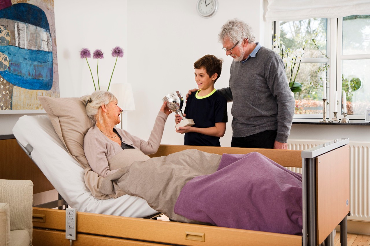 Mevrouw in een hoog-laag bed met trotse kleinzoon