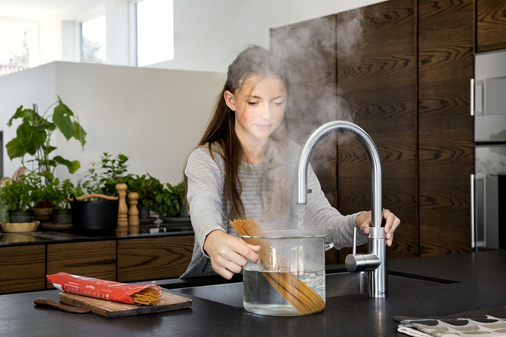 meisje gebruikt kokend water uit quooker-kraan voor pasta