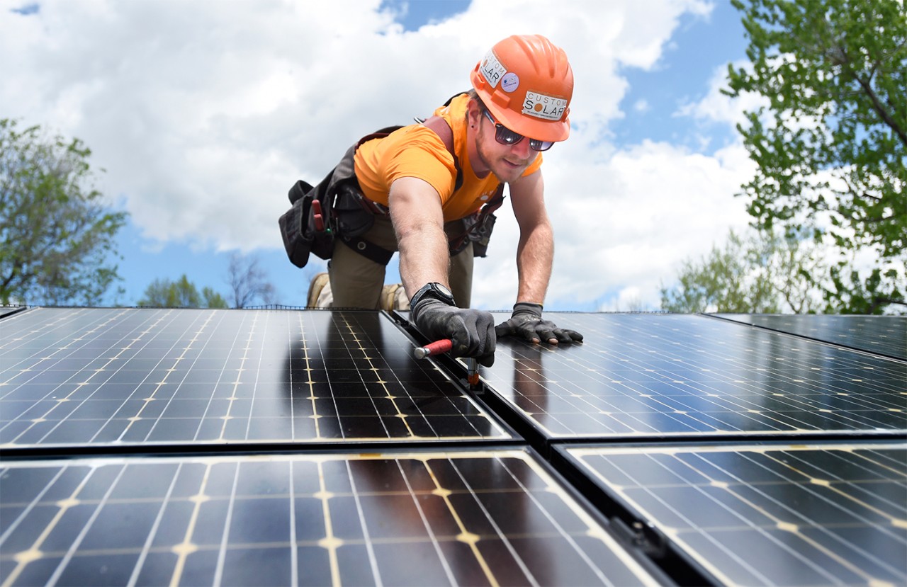 Installateur plaatst zonnepanelen op een rietdak